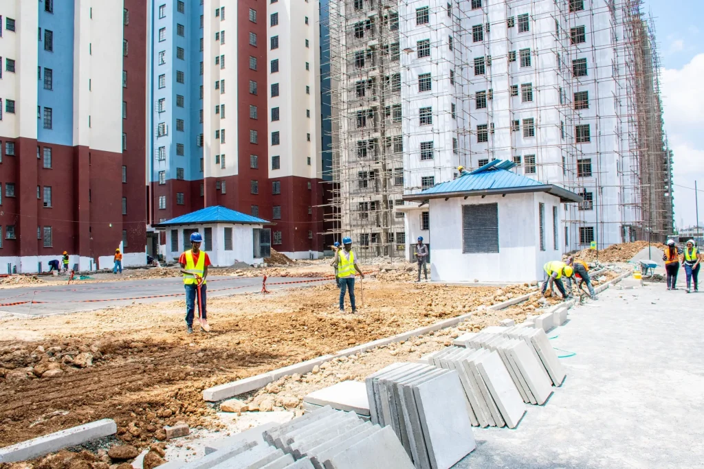Residential apartment buildings under construction with workers on-site.